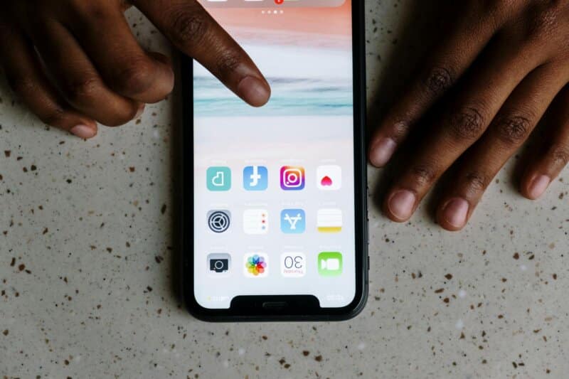 Close-up view of hands interacting with social media apps on a smartphone screen.