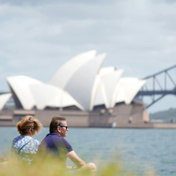 A serene scene of a couple enjoying the view of the iconic Sydney Opera House by the water.