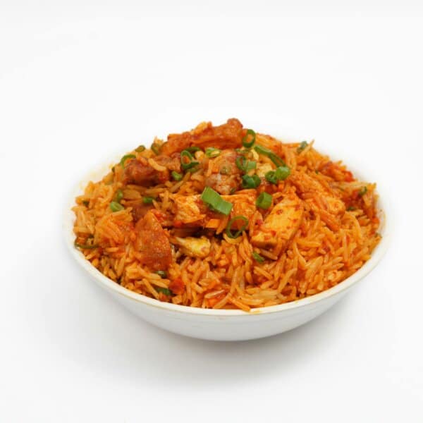 A flavorful bowl of spicy tandoori chicken biryani garnished with green onions.