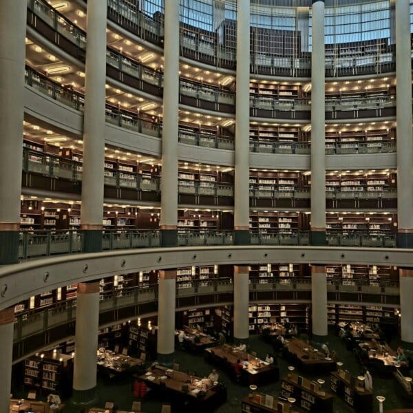 Expansive circular library interior featuring multi-tiered bookshelves and reading tables.